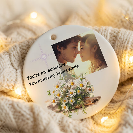 Hand holding a personalized ceramic photo ornament, custom double-sided Christmas tree decoration with family portrait.